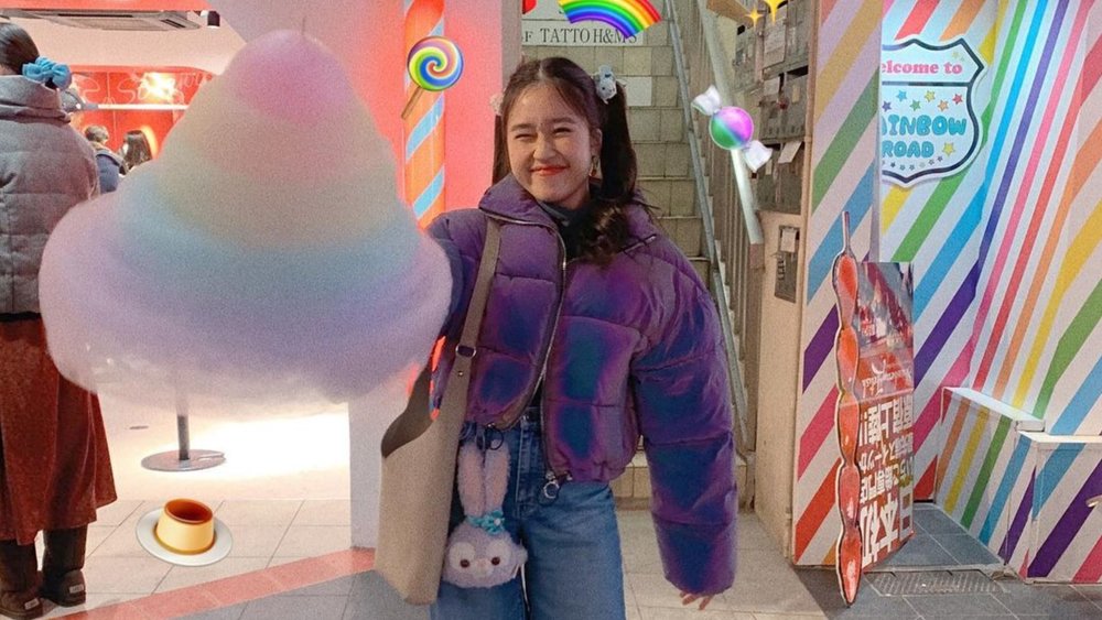 A little girl happily smiling while holding massive cotton candy