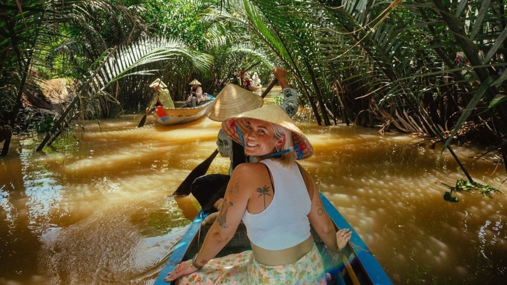 a woman smiling as she canoes through the Mekong Delta