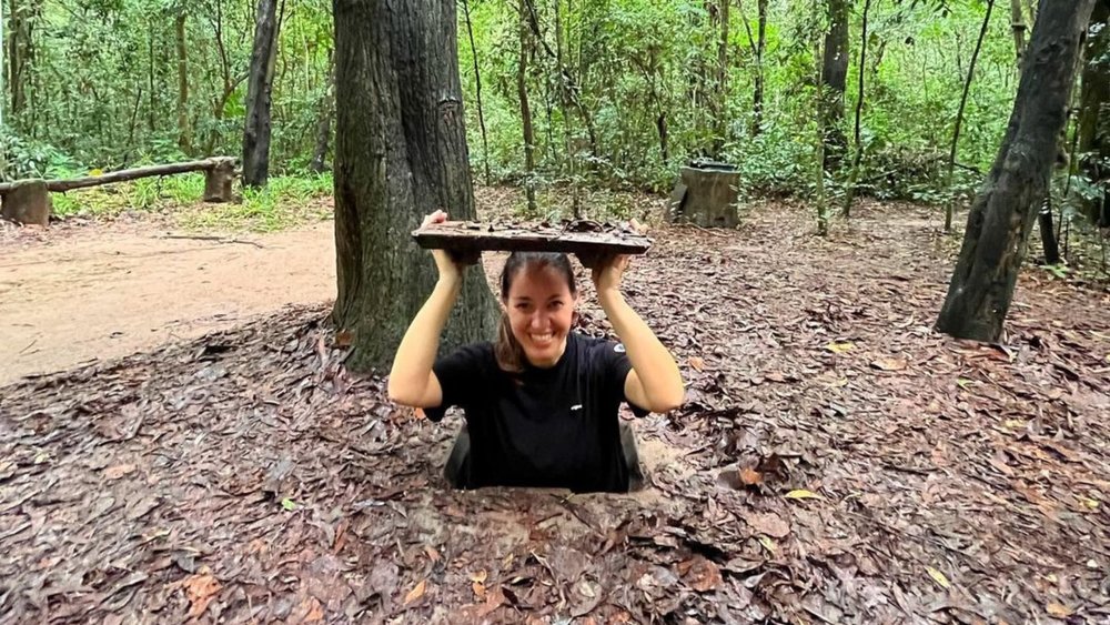 a woman smiling as she explores the Cu Chi Tunnels