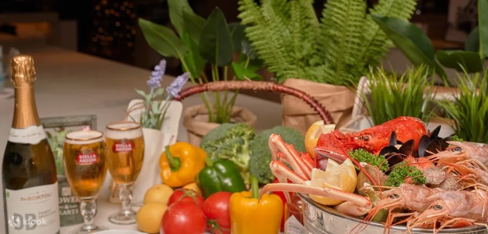A bowl of seafood, colorful bell peppers, and a bottle of champagne