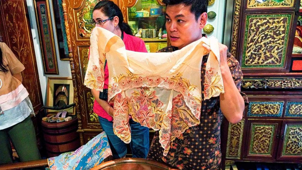 a man holding up an artifact at the The Intan Peranakan Heritage Museum Tour