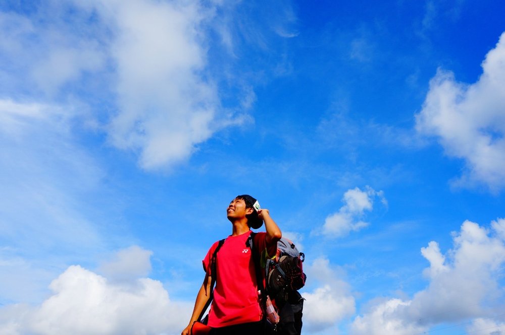 空を見上げるバックパッカー