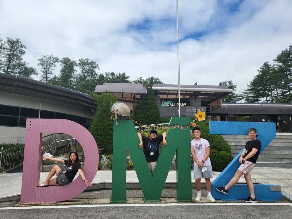 People posing for a photo with giant DMZ letters