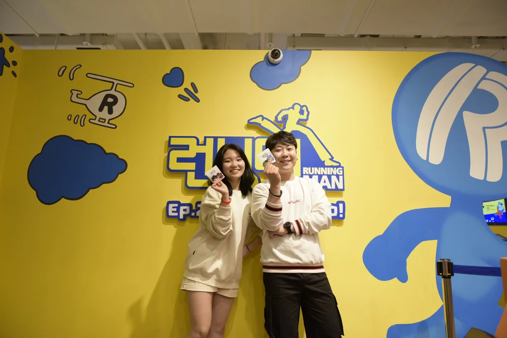 A man and woman in front of a Running Man signage