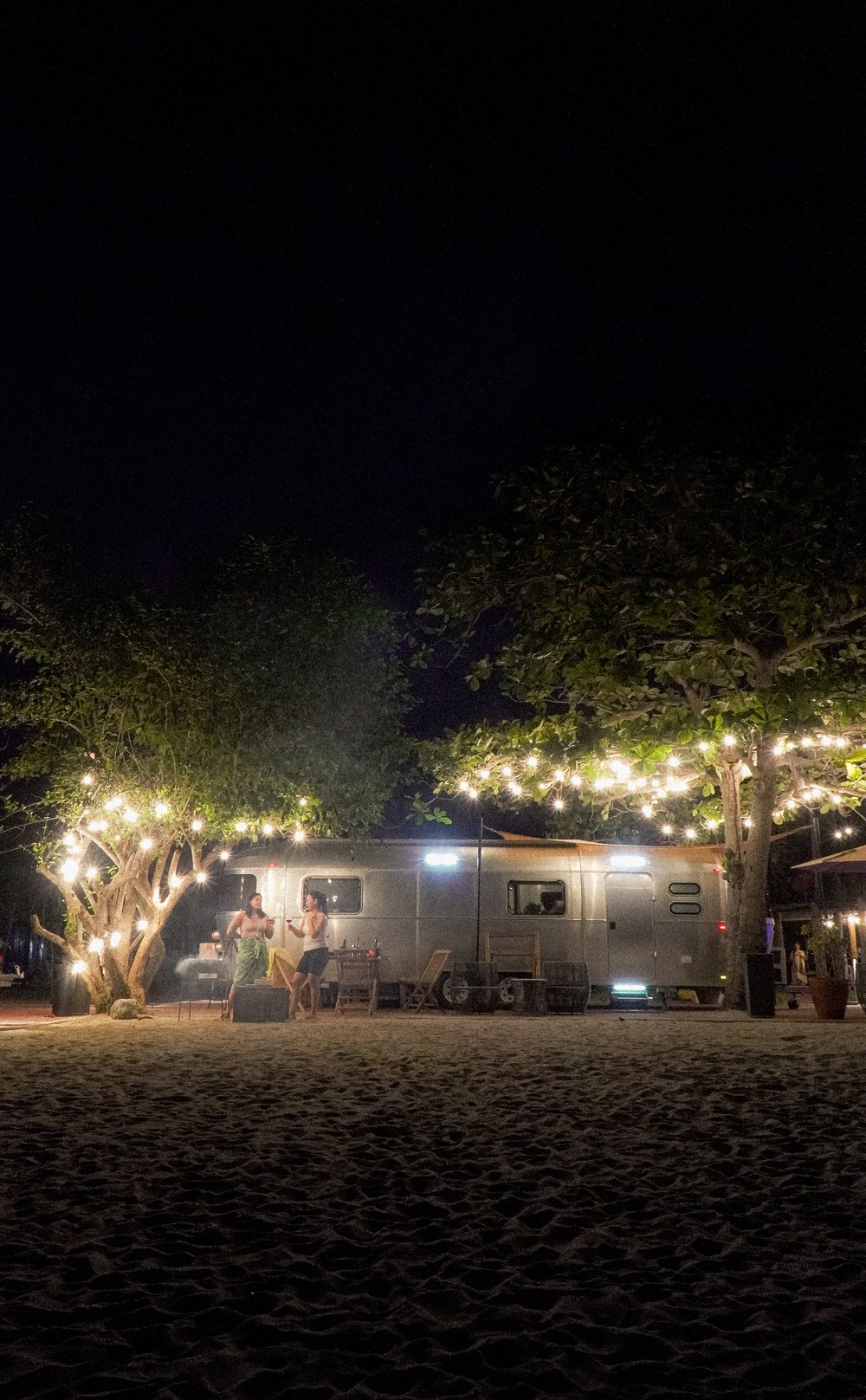 two girls grilling by camper van at night