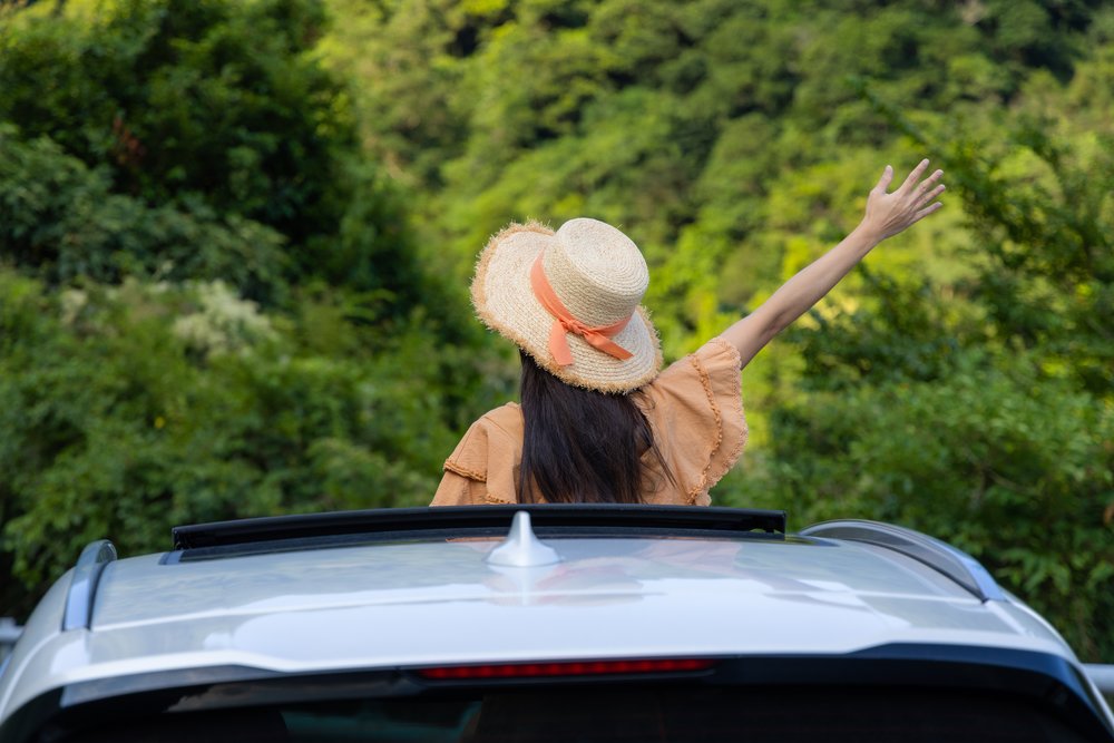 Woman standing while inside the car and raising her arm
