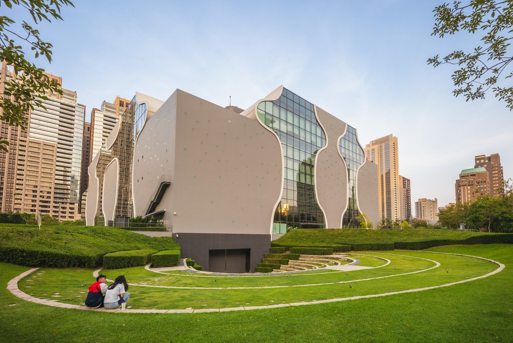 Two people sitting on the grass overlooking the theater's exterior