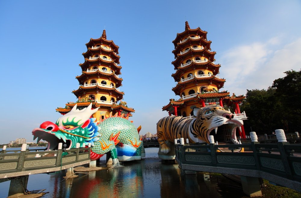 a dragon pagod and a tiger pagoda side by side by a lake