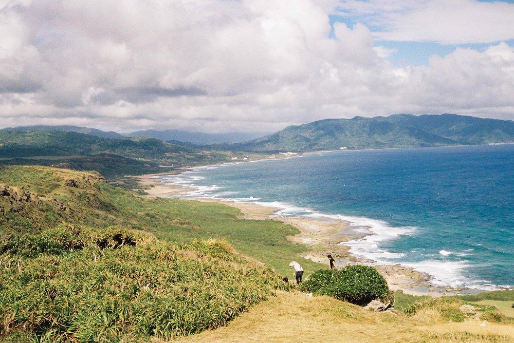 shoreline with mountains and two people by the sand
