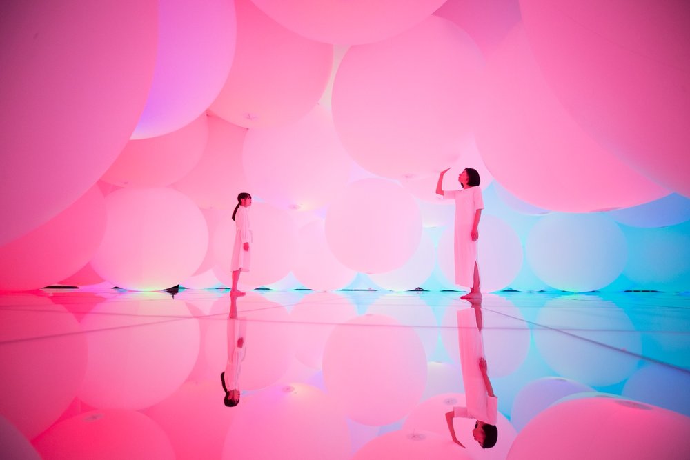 two people touching giant pink balloons