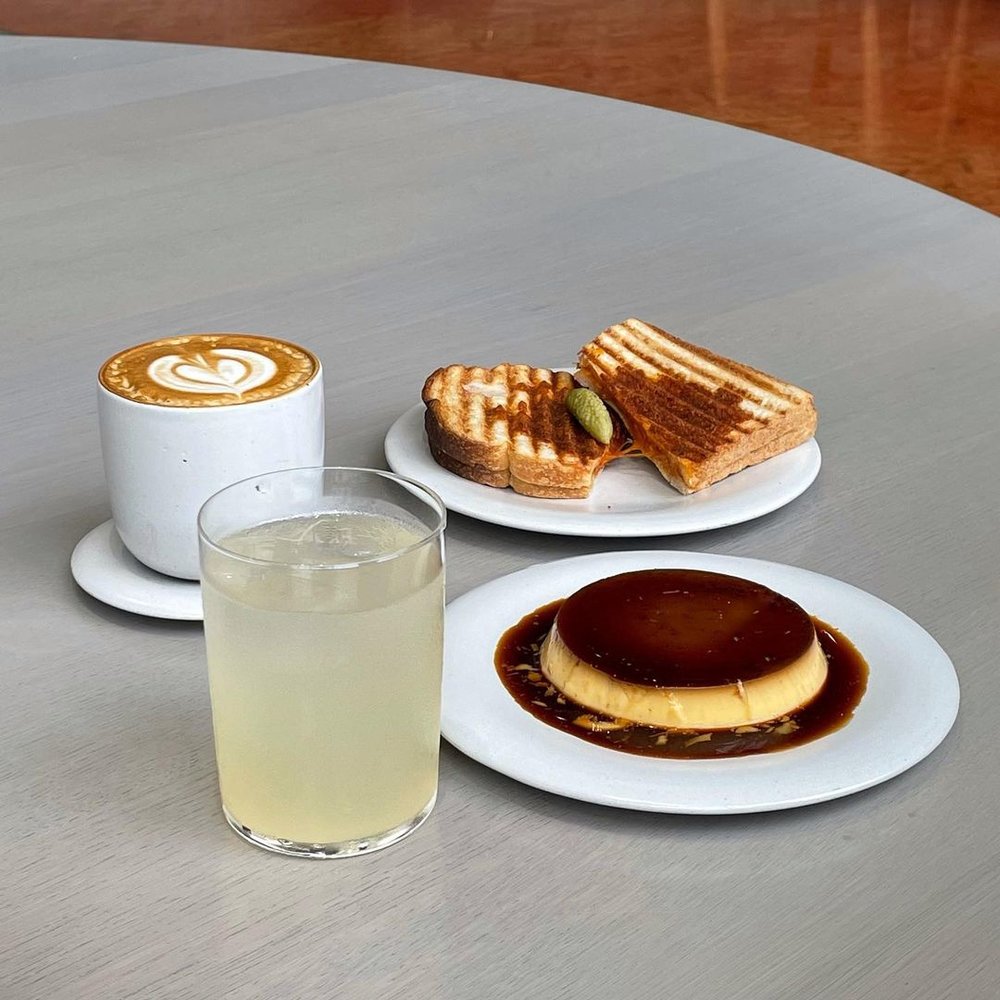 coffee, sandwich, iced tea, and flan on a table