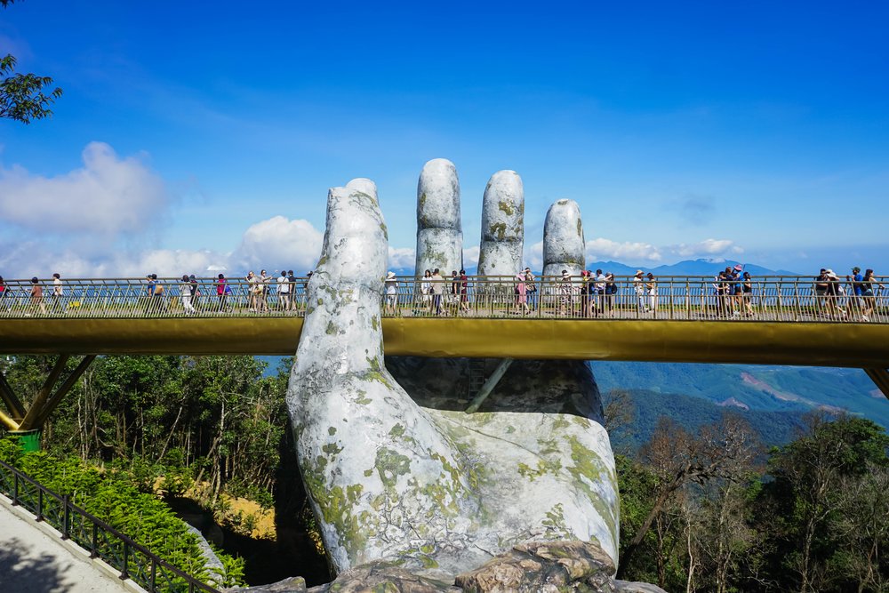 large hand statue and a bridge that goes over it 
