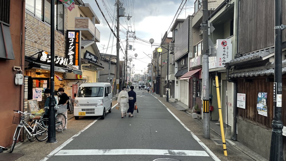 two ladies in kimonos walking along a street in kyoto