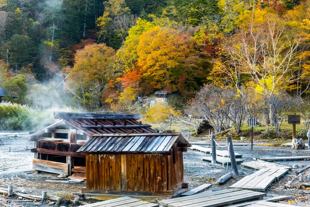 a onsen town surrounded by trees in autumn colours