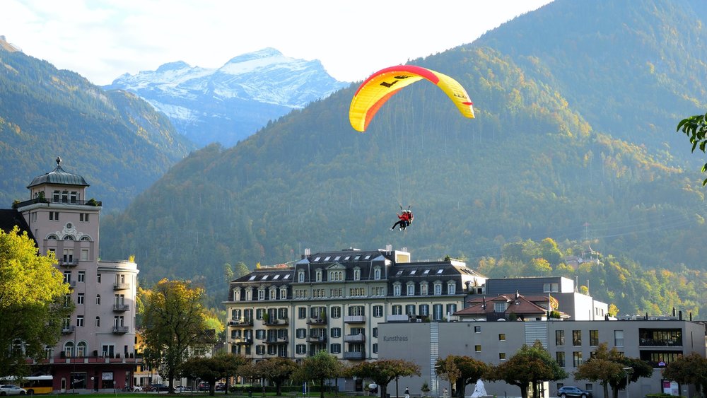 people paragliding in a swiss town