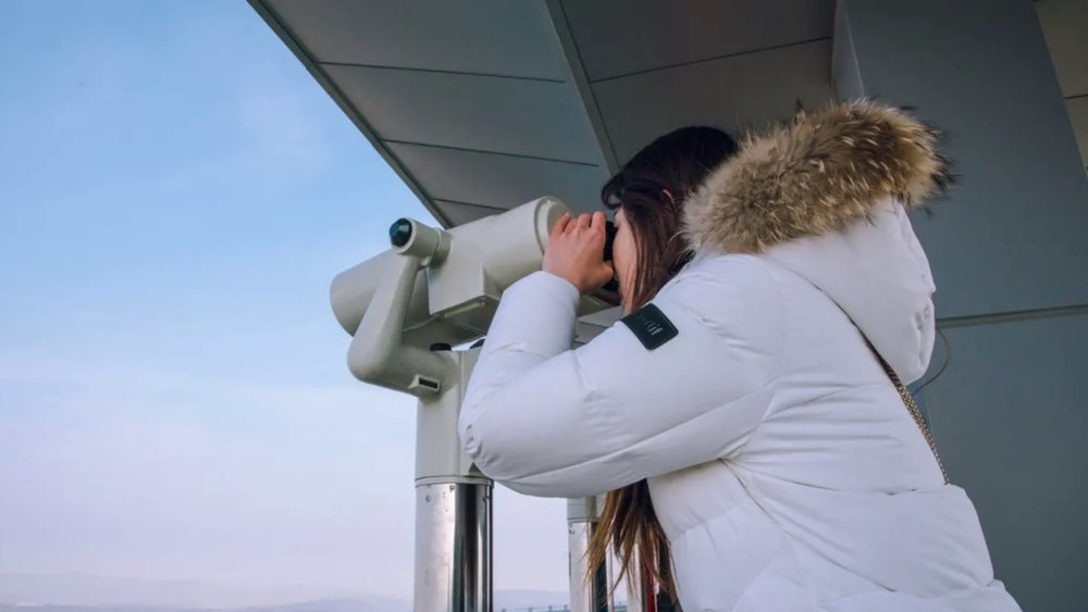 a woman looking through a tower viewer at Dora Observatory