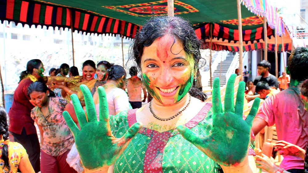 a woman holding out her green hands at The Holi Festival