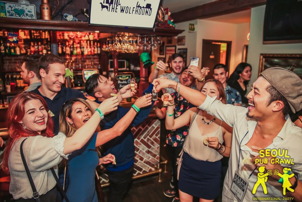 a group of people in a bar smiling and raising their glasses