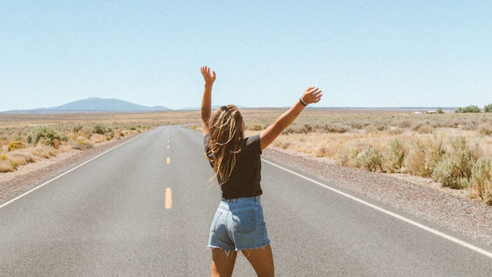 a woman in the middle of the road with her hands up in the air