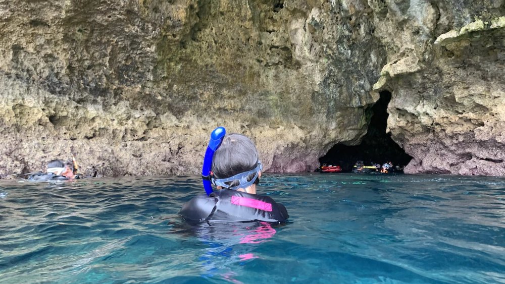 a man swimming at the entrance of the Onna Village Blue Cave