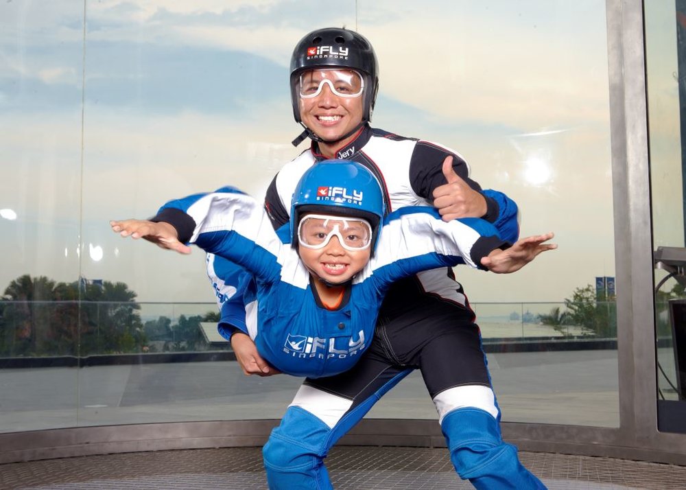 A kid floating and an adult standing in a tube