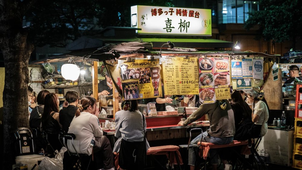 people sitting around a street stall at night
