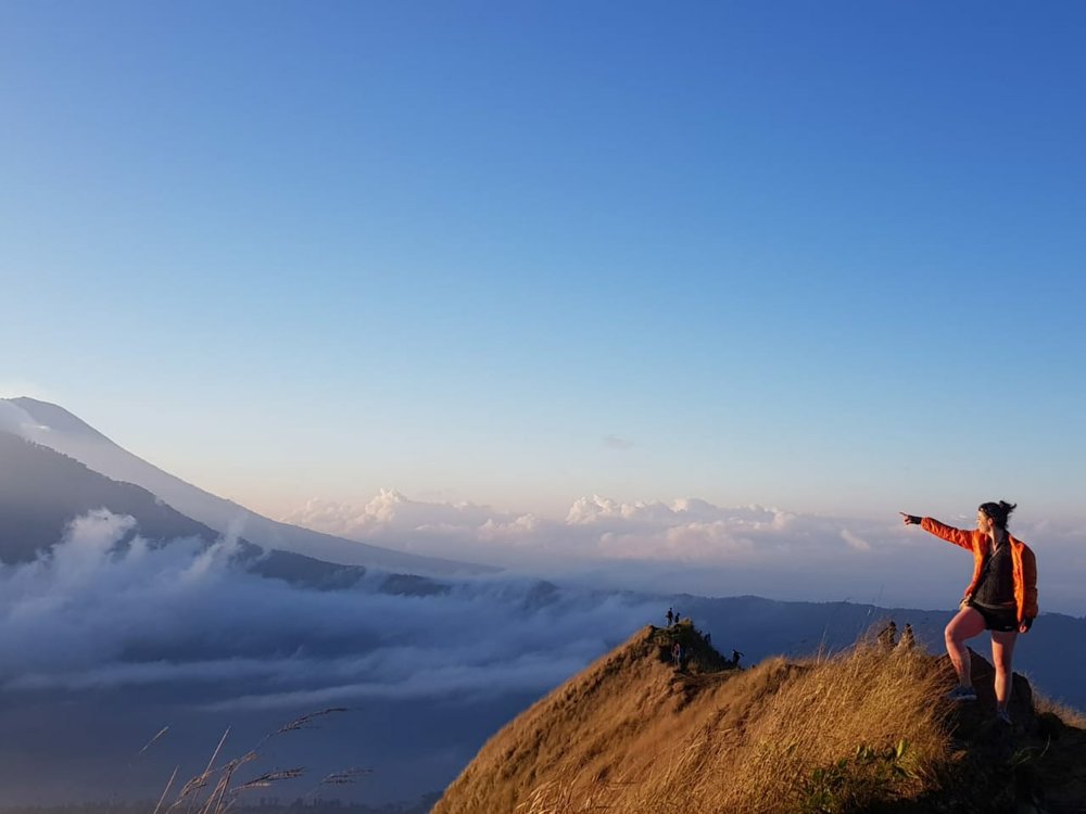 woman pointing to the massive view while up on a hill