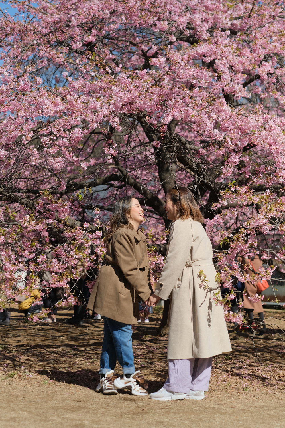mom and daughter behind cherry blossom tree