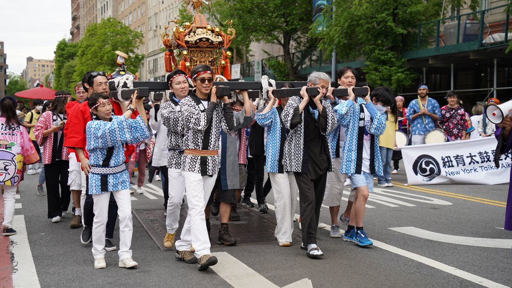 group of people carrying small shrine down a street