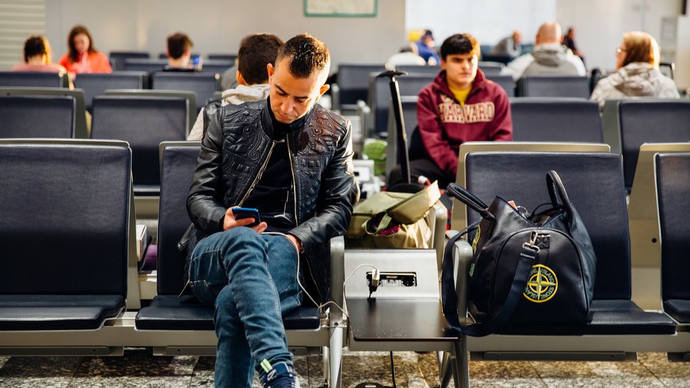 man sitting at the airport looking at his phone