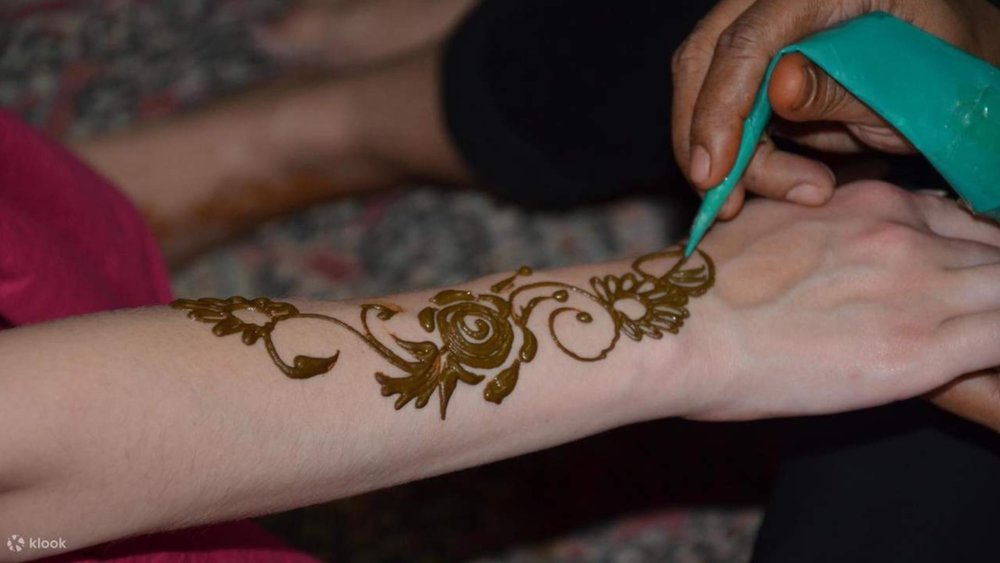 a woman painting henna on a tourist's hand