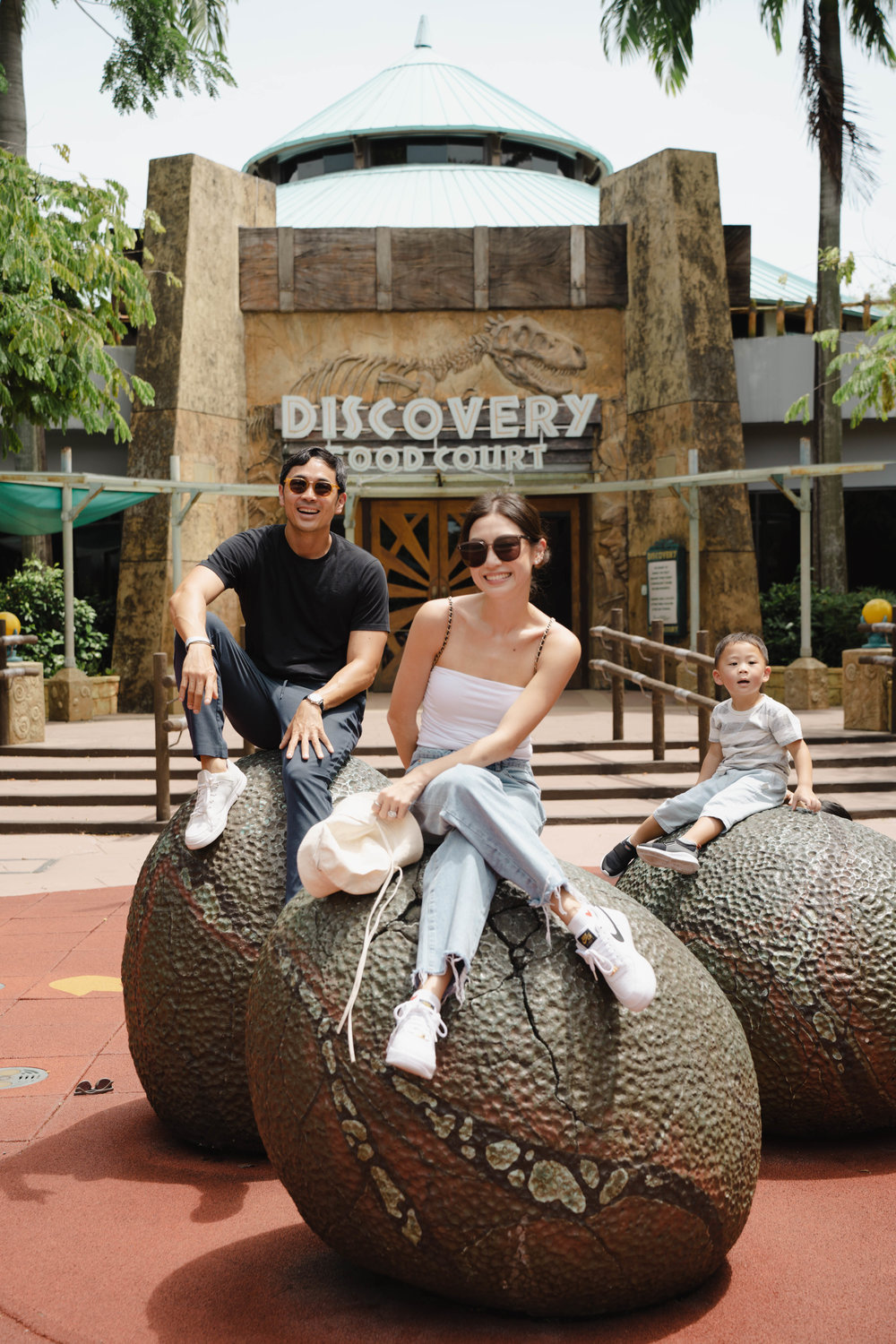 kryz uy and family sitting on dinosaur egg sculptures