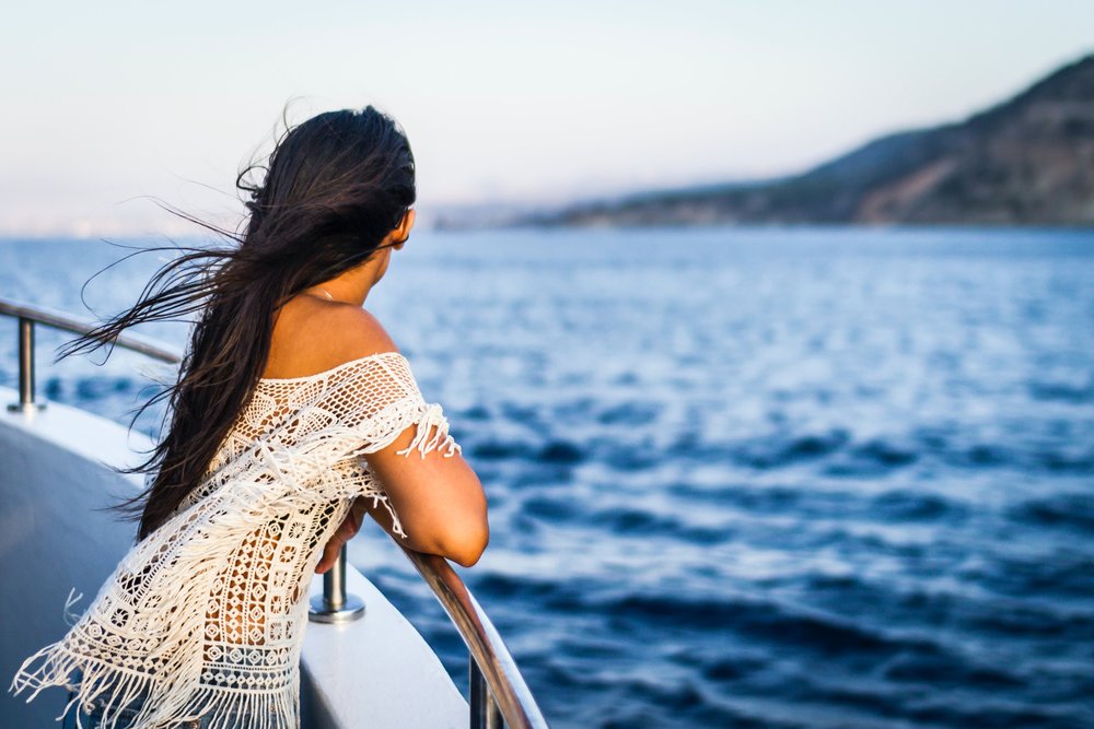 lady on the railing of a boat and looking out to the sea