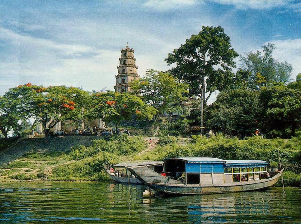 a boat by the river with an historic pagoda overlooking the grounds