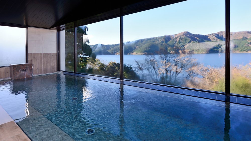 a pool with wide windows and a view of mountains and a lake