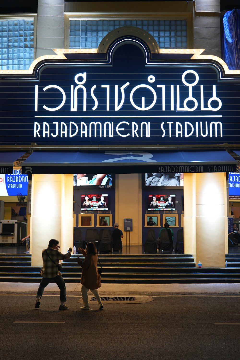 Man and woman play fighting at Rajadamnern Stadium entrance 