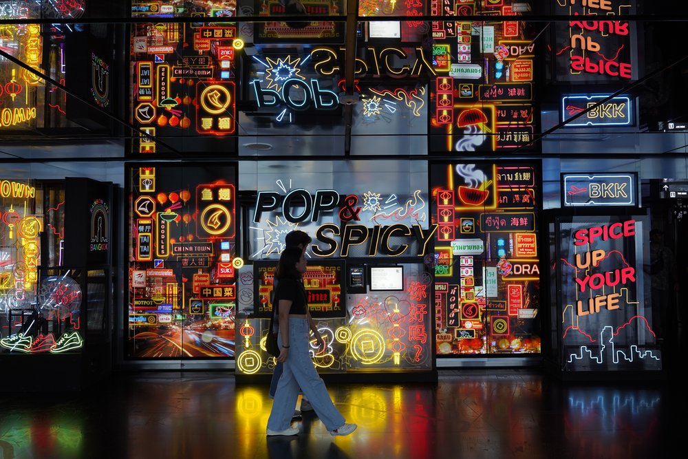 Man and woman walking beside neon wall