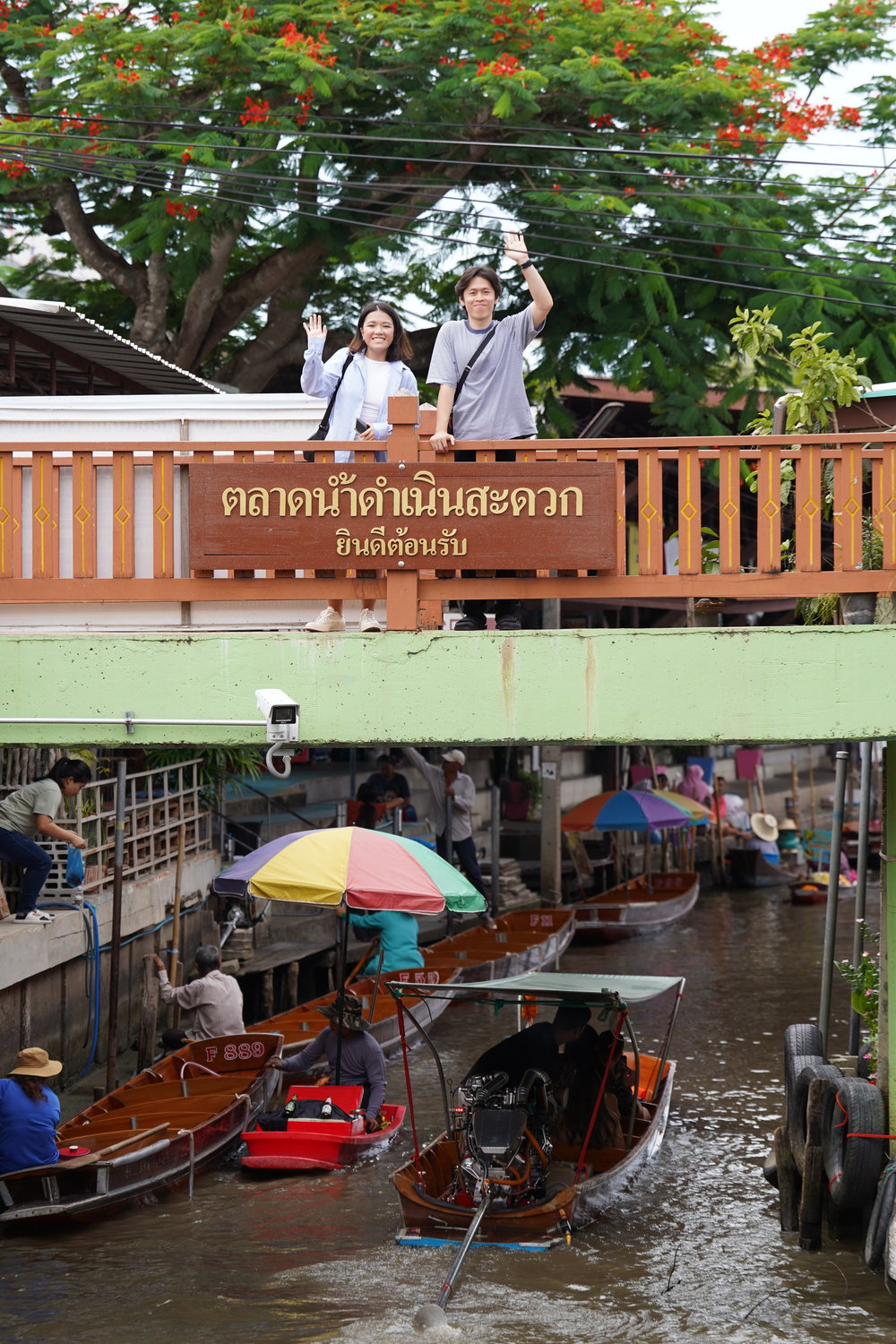 Man and woman waving while standing on a bridge