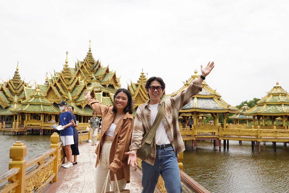 Man and woman smiling and showing the views on a bridge