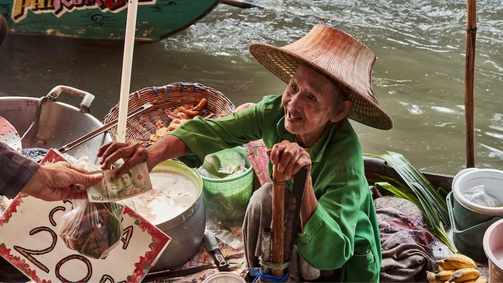 Old market woman is selling exotic snacks at a floating market. Credits: Norbert Braun on Unsplash