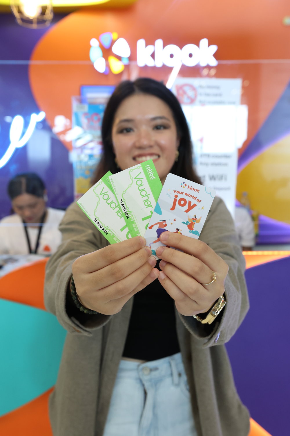 Girl holding a BTS Skytrain card and two vouchers