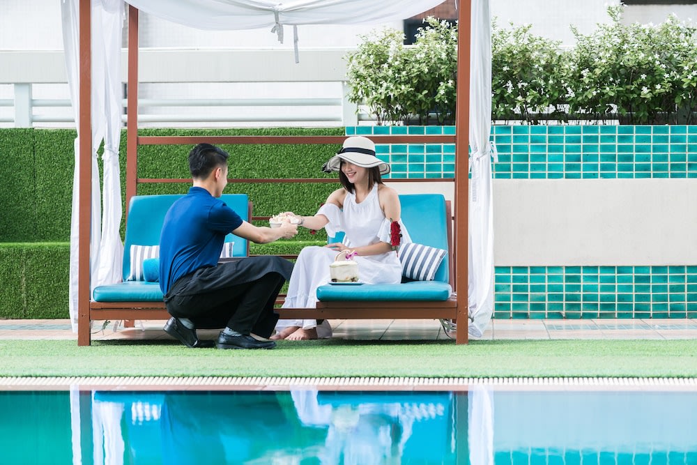 Staff giving customer a drink by the pool
