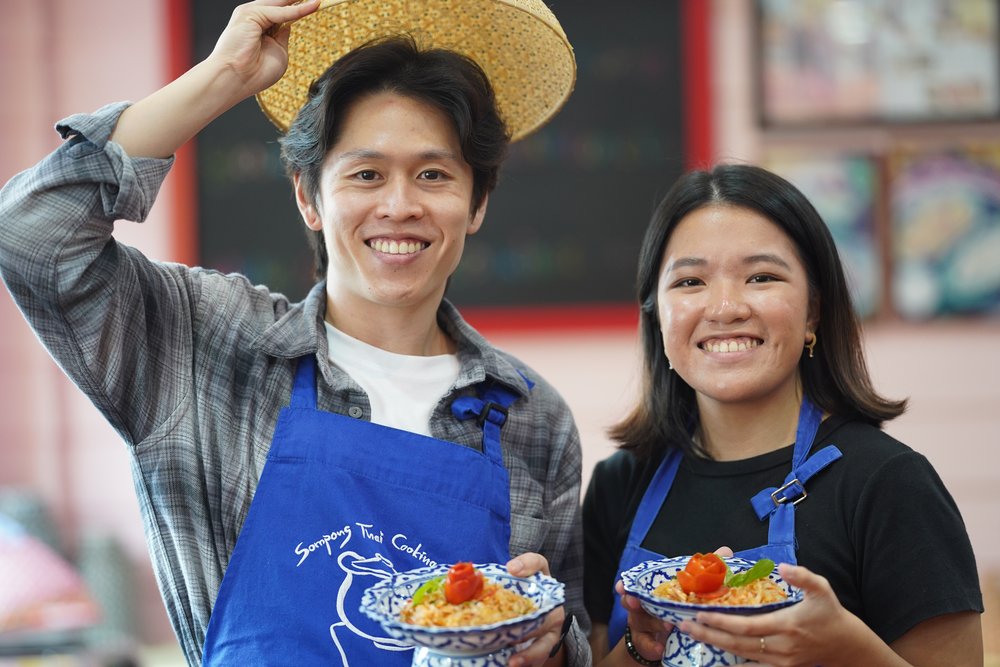 Man and woman holding bowls of food and smiling