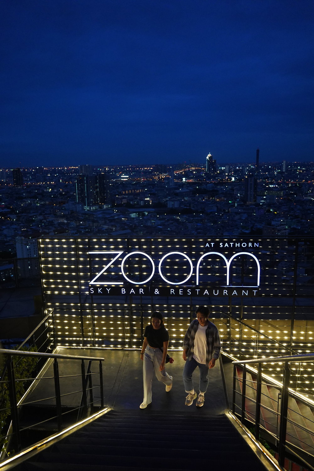 Man and woman by Zoom Sky Bar's signage
