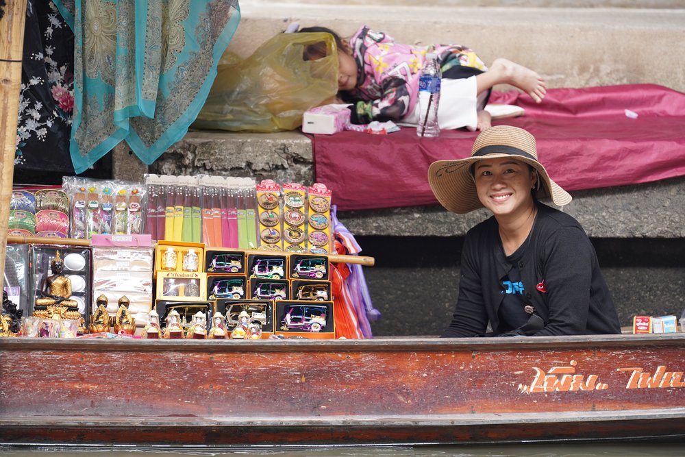 Woman on a boat selling many Thai items
