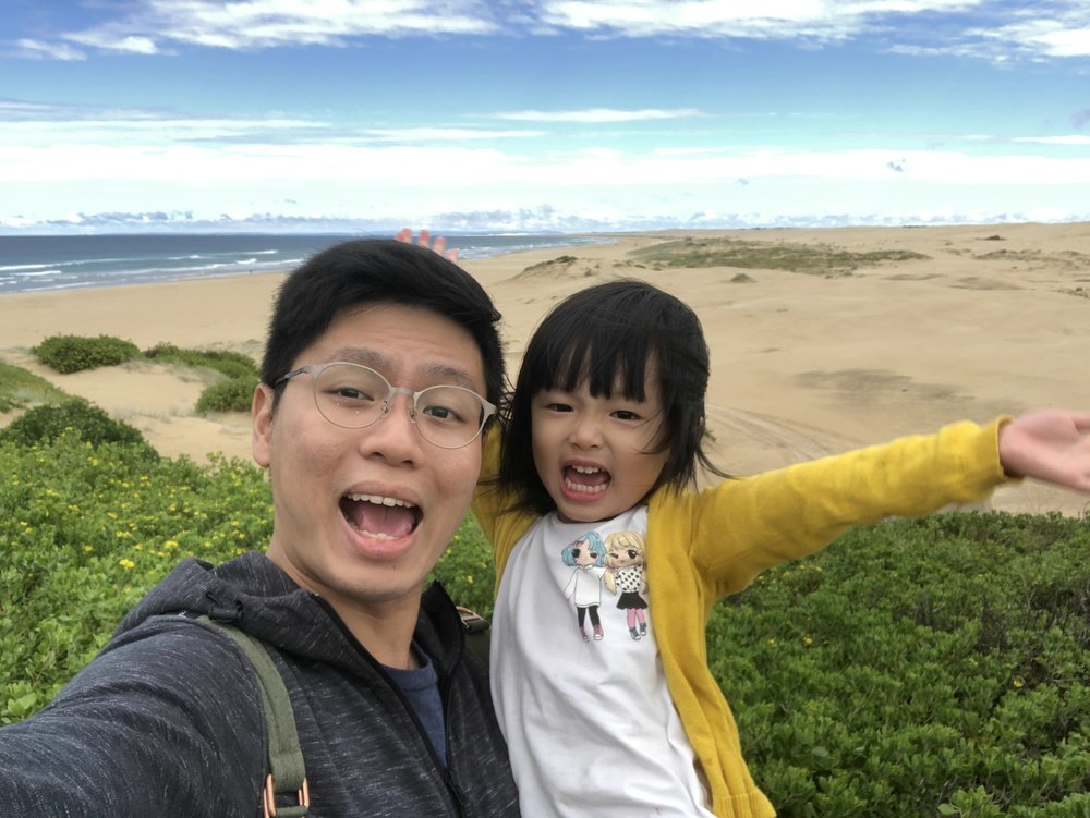 father and daughter pose for a picture with a wide view of nature behind them