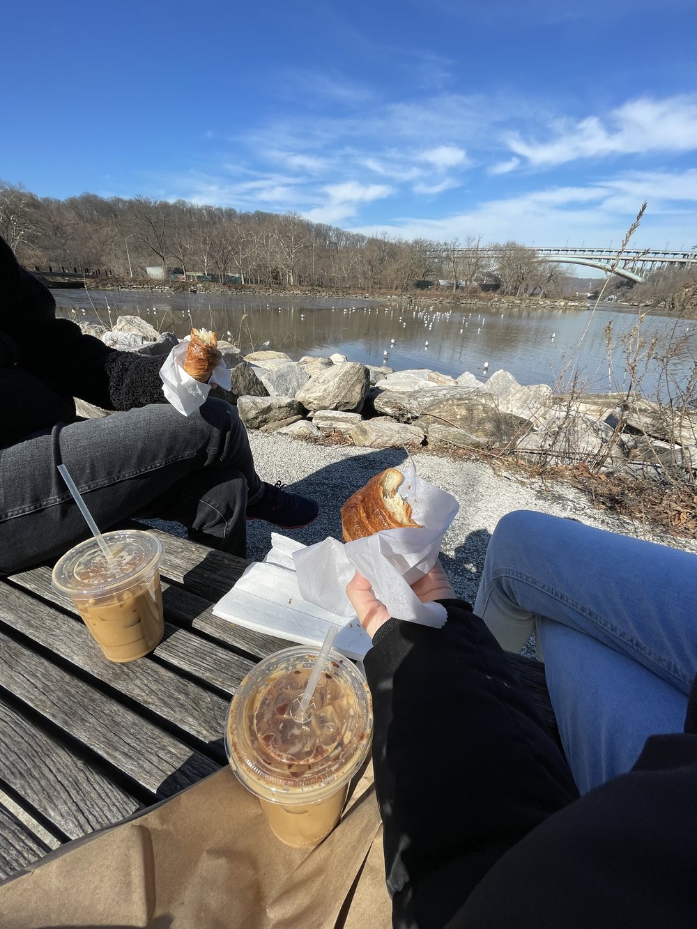 two people having coffee and croissants by the river in winter