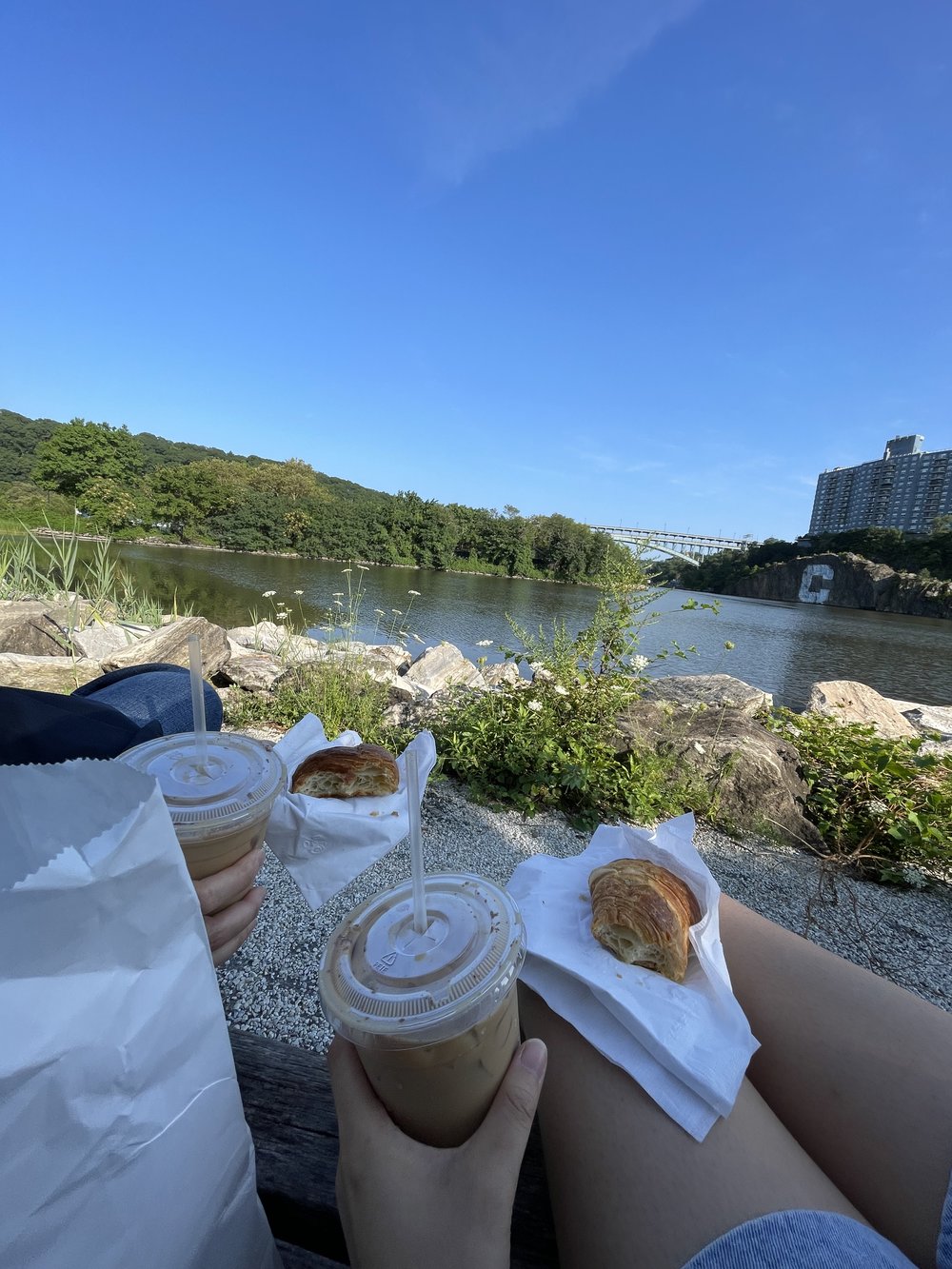 two people having coffee and pastries by the river in summer
