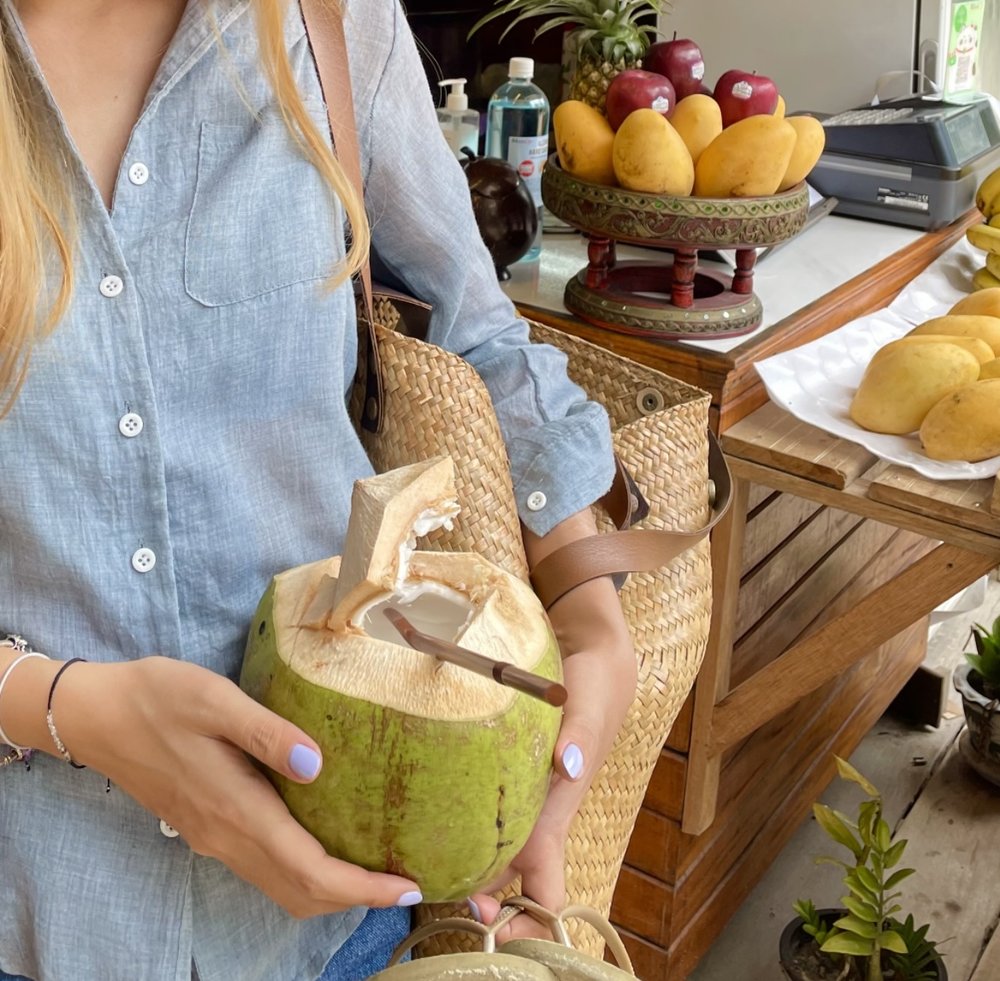 woman holding a freshly opened coconut with a straw