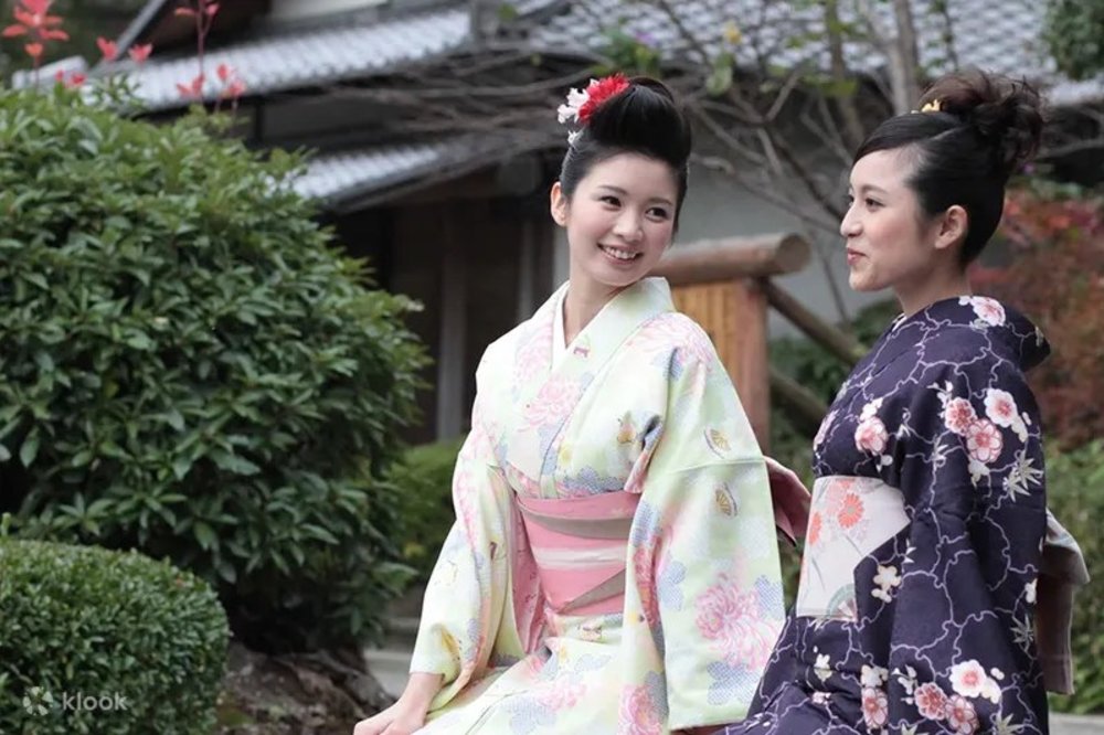 Two smiling women in kimono sitting down
